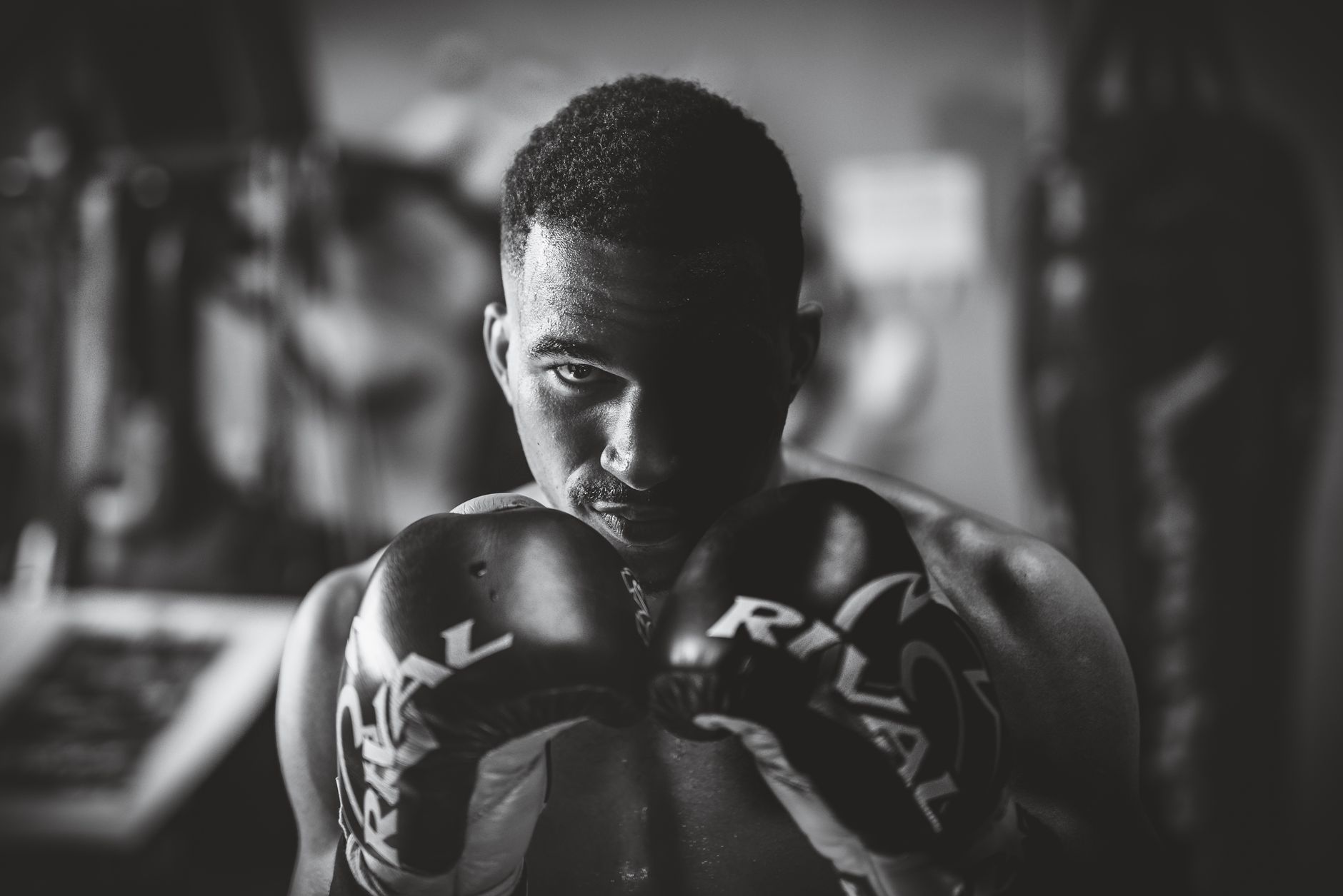 Dramatic black and white portrait of a focused boxer in a gym setting, highlighting strength and determination.